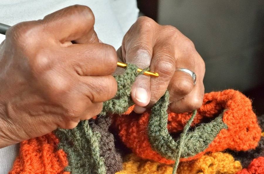 Manos tejiendo crochet con aguja y lana